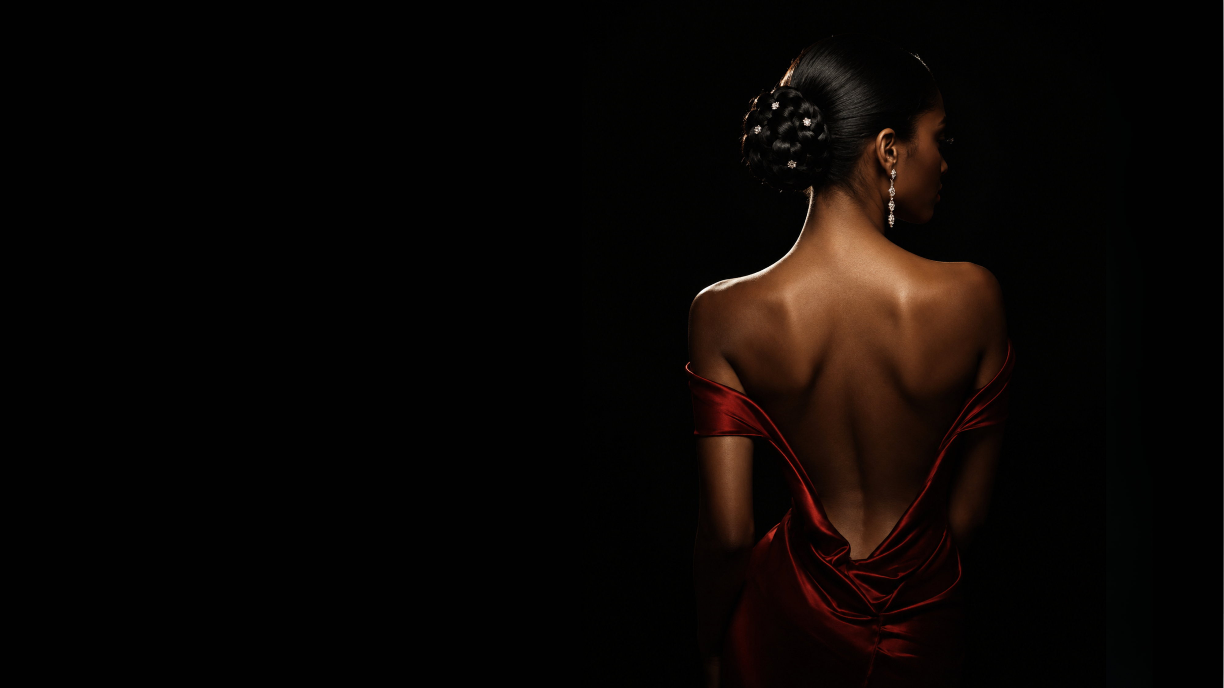 A woman in a red evening gown against a black backdrop